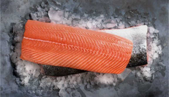 Świeży filet z łososia ze skórą ułożony na pokruszonym lodzie.