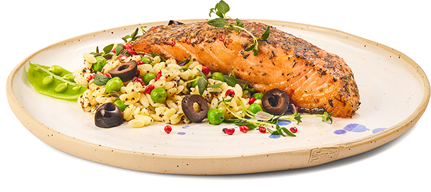 Pieczony filet z łososia podany na jasnym talerzu z orzo, zielonym groszkiem, czarnymi oliwkami i ziołami.